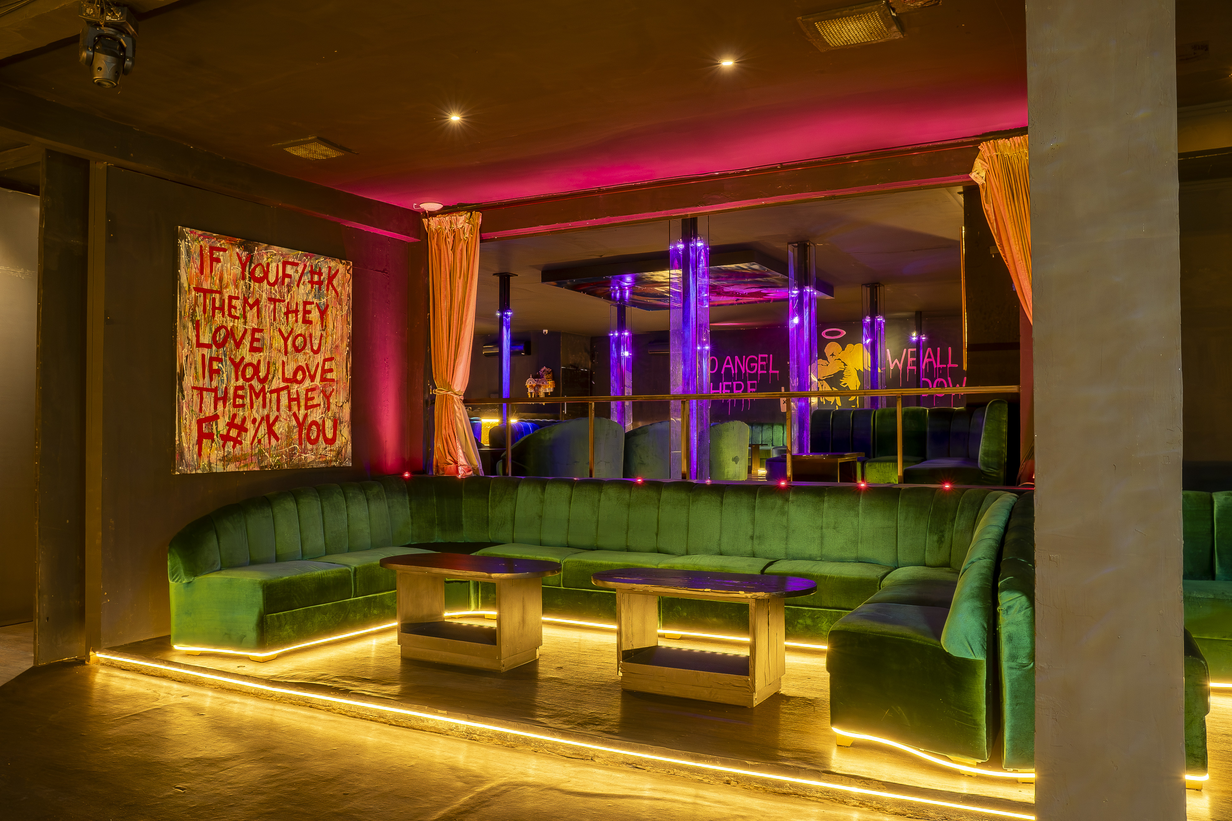 Nightclub VIP area with green velvet curved seating and LED lighting